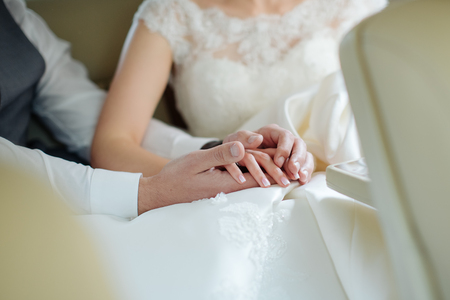 Hands of the groom touch the fingers of the bride, her palms in his palms. Light, gentle, sensual, mysterious touch.の写真素材