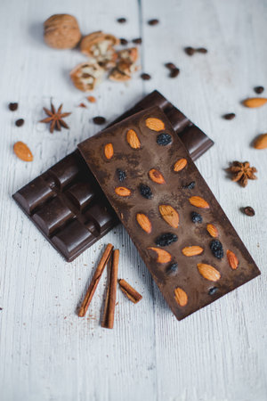 chocolate bar filled with different berries and nuts without heat treatment lie old wooden table...