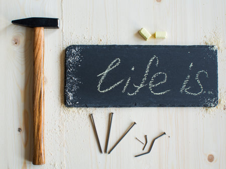 Hammer, nails and yellow crayons and a tablet of stone with an inscription life it on a wooden surface are ready for useの写真素材