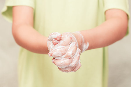 Front view on kid hands in soapsuds, personal skincare concept