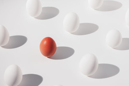 one brown egg among several white eggs on a white background, isometric composition