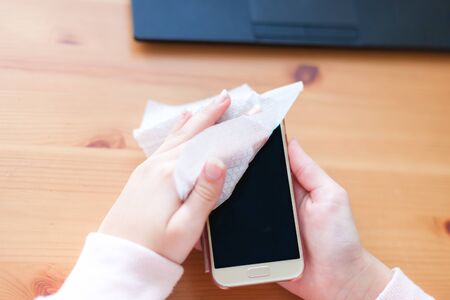 Women's hands wipe their phone with an antibacterial napkin, virus protectionの写真素材