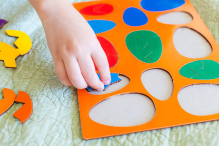 Close up of child hand collecting puzzle in the form of Easter eggs