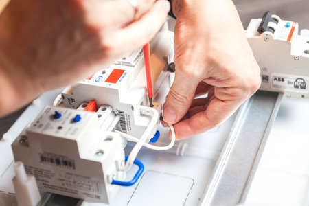 SAINT-PETERSBURG, RUSSIA - DECEMBER 19, 2019 Mens hands close-up. Installation of an electric meter. Man using screwdriverのeditorial素材