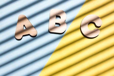 Wooden letters ABC on blue and yellow background. The concept of the importance of education. Background with diagonal shadows.の写真素材