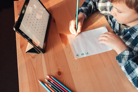 Modern child uses app on tablet to study and draw at home, distance learning