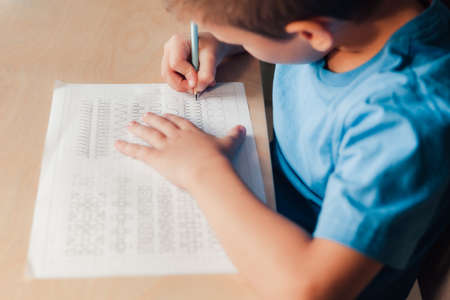 Close up of cute child doing his homework. Kid writing different lines by pencil. Children education concept.の写真素材