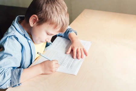 Close up of cute boy doing his homework. Kid writing different lines with pencil. Children education concept.の写真素材