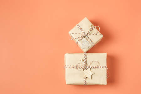 Two Christmas presents wrapped in craft paper on terracotta background. Copy space. Top view.の写真素材