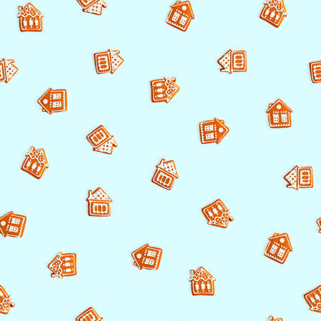 Gingerbread houses on blue background. Seamless Christmas pattern. Brown homemade biscuit with white icingの写真素材
