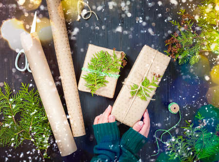 Zero waste Christmas. Wrapped Christmas gifts in craft paper with thuja branches. Beautiful Christmas lights. Top viewの写真素材
