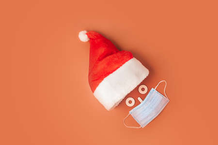 Festive Santa Claus made from blue medical mask and Christmas hat on orangeの写真素材