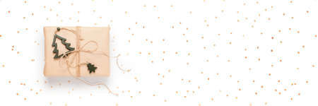Gift box wrapped in craft paper with decor on white background, long banner with kraft confettiの写真素材