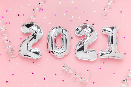Foil balloons in form of numbers 2021. Silver color air balloons on pink background. Flat layの写真素材