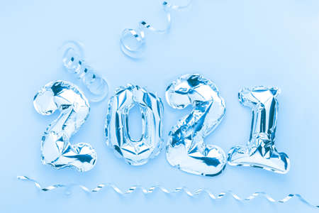 Foil balloons in form of numbers 2021. Silver color air balloons on blue background. Flat lay with copy spaceの写真素材
