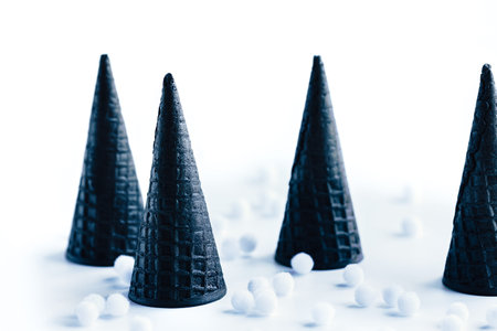 Concept of Christmas trees made of edible waffle cones standing on white background with snow ballsの写真素材