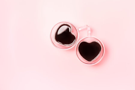 Two cute heart shaped coffee mugs on pink background with copy space. Valentines Day flatlay composition.の写真素材