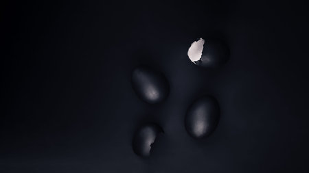 Some black painted Easter eggs on black background, flat lay with copy space