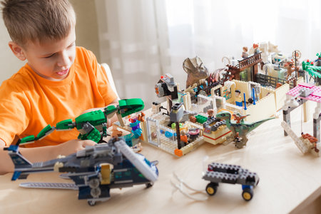 SAINT-PETERSBURG, RUSSIA - NOVEMBER 26, 2020 Boy play with lego bricks sitting by desk, world of dinosaurs built by childのeditorial素材