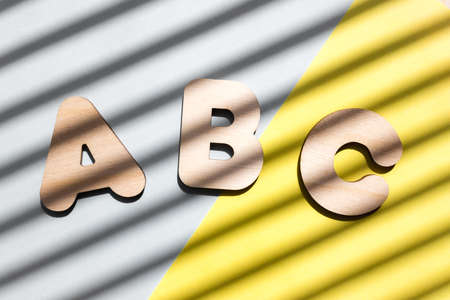 Wooden letters ABC on blue and yellow background. The concept of the importance of education. Background with diagonal shadows.の写真素材