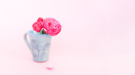 Nice small bouquet of roses in tea cup on pink background with copy space