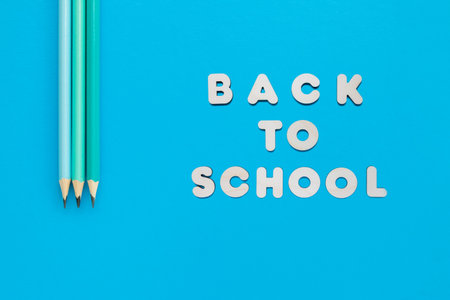 Tree pencils and text Back to school on blue background, minimalistic concept. Copyspace and top...