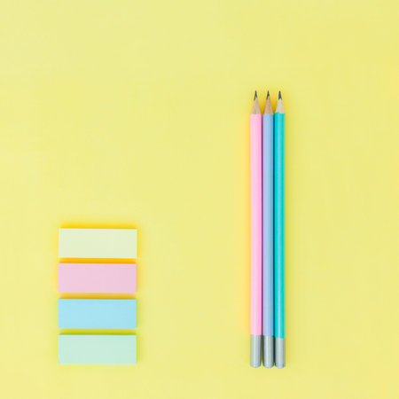 Three colored lead pencil and pastel colored sticky notes on yellow paper backgroundの写真素材