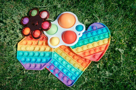 Some pop it toys laying on green grass, popit and simple dimple game for anti stress activitiesの写真素材