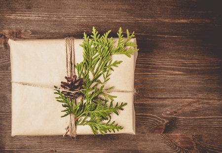 Christmas zero waste concept. Cozy gift box wrapped in craft paper and decorated with green cypress...