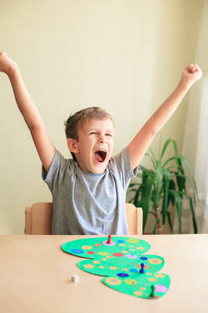 happy child enjoys victory in the board game. Board game in form of Christmas tree. Concept of spending time with familyの写真素材
