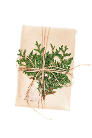 Gift box wrapped in craft paper decorated with pine cone on white backgroundの写真素材