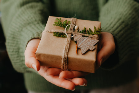 Female hands holding nice gift box. Woman giving wrapped in black paper present. Cozy gift wrapping designの写真素材