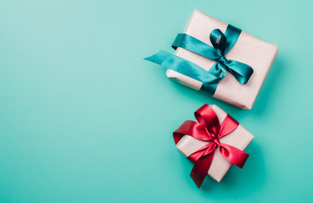 Two Christmas gift boxes with green and red ribbon on light blue background