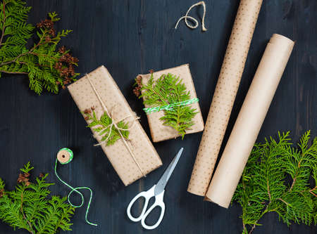 Wrapping Christmas gifts in craft paper with thuja branches. Preparing for the Christmas holidays. Top viewの写真素材