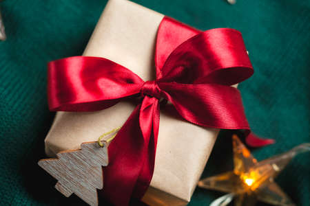Nice Christmas gift boxe wrapped in craft paper with red ribbon on dark green knitted backgroundの写真素材