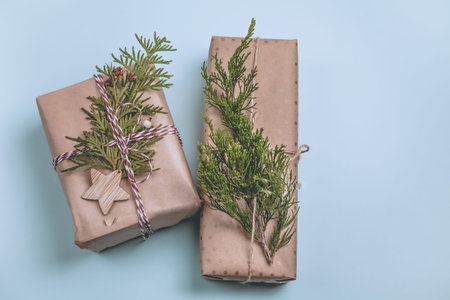 Nice presents wrapped in craft paper and decorated with cypress branch laying on blue paper background. Flat lay, top viewの写真素材