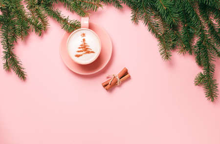 Top view of cup of latte with art in shape of Christmas tree on pink background with branch of fir tree and gift box. Copy space for your textの写真素材