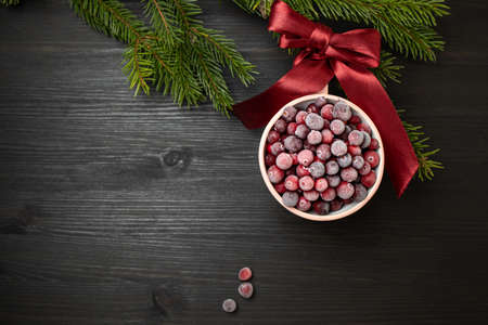 Christmas bauble made from cup of frozen cranberries . Copy space on dark wooden backgroundの写真素材