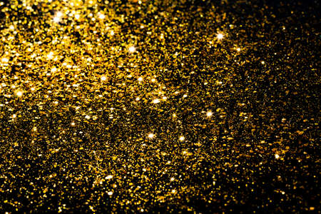 Golden bokeh background. Golden glitter on a black background.Festive New Year and Christmas shiny glitter layout.の写真素材