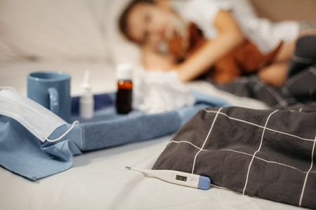 Bottle with antipyretic syrup, nasal spray and thermometer on napkin. Small DoF, focus on the...