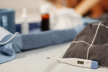 Bottle with antipyretic syrup, nasal spray and thermometer on tray. Small DoF, focus on the...