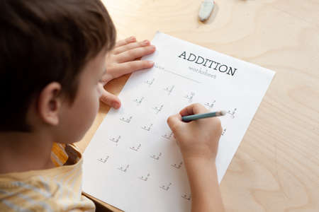 A schoolboy doing math lesson sitting at desk in the children room,top view, close upの写真素材