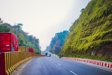 Bayezid link road highway passing through lush green hills with trucks, cars, and motorcycles, showcasing a blend of modern roadways and natural beauty at Chattogram, Bangladesh.の写真素材