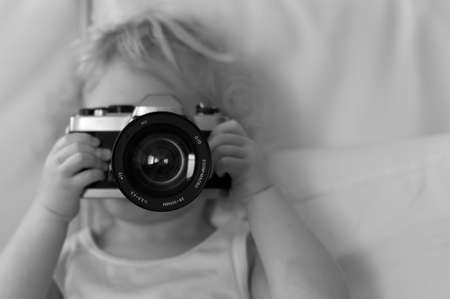 little blonde girl shooting with single reflex cameraのeditorial素材