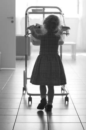 little girl pushing her newborn baby sister in a wheelchairの写真素材