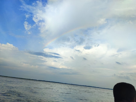 A man looks at the rainbow in the sky above the sea.の写真素材