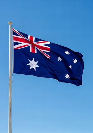Australian flag waving in the wind on a clear blue sky background.の素材