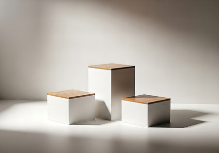Three white cubes with wooden tops stand on a white surface, bathed in soft, diffused light, creating a minimalist and elegant display setup.の素材