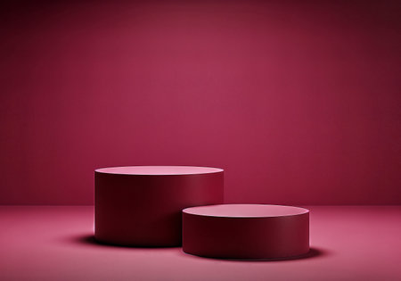 Two burgundy cylindrical platforms stand in a studio setting, creating a minimalist product display with soft lighting and a matching burgundy backdrop.の素材