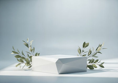 A modern, faceted white podium provides a clean stage for product display, elegantly framed by delicate green leaves against a serene, cool-toned studio background. 3D render.の素材